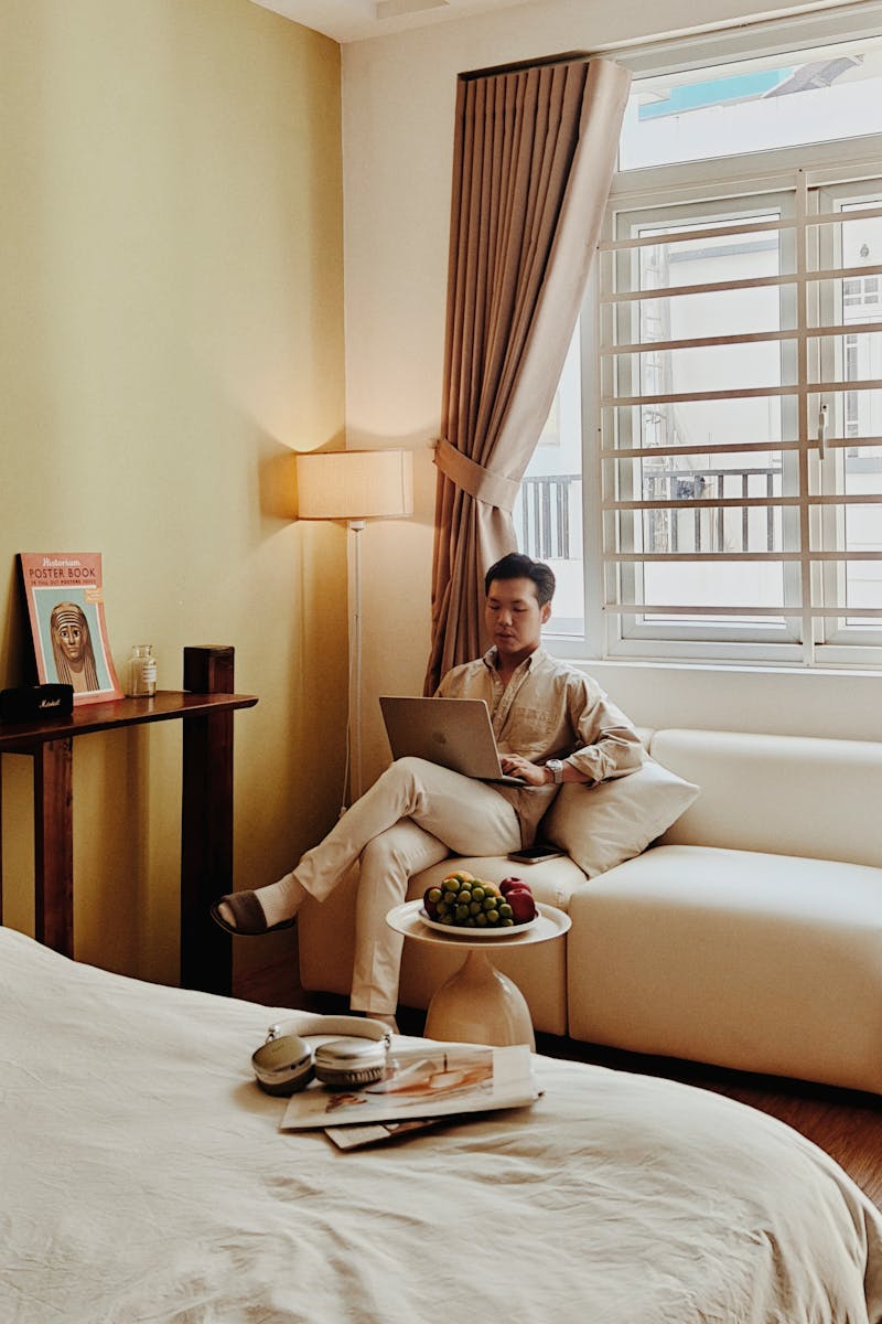 A cozy Airbnb room in Vietnam with a man relaxing and working on a laptop, creating a serene atmosphere.