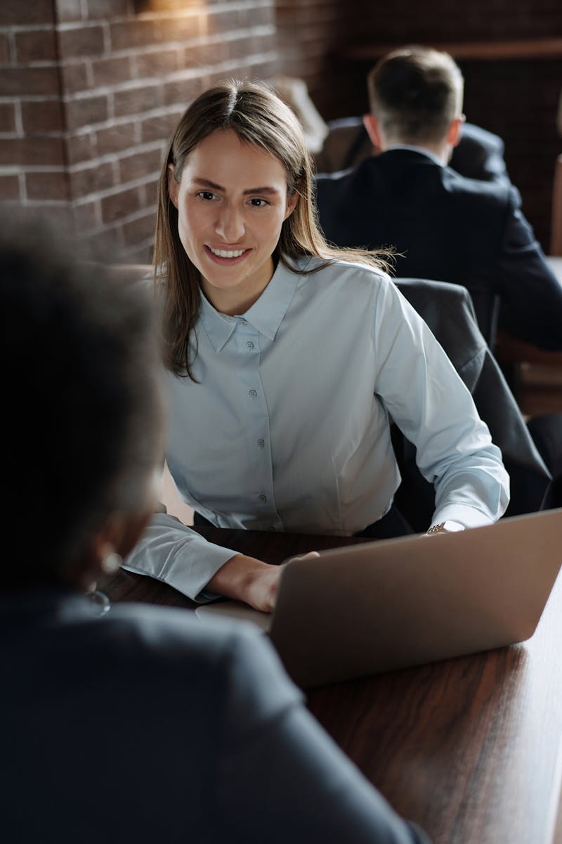 Businesswoman in a dress shirt smiling during a meeting in a stylish office setting.